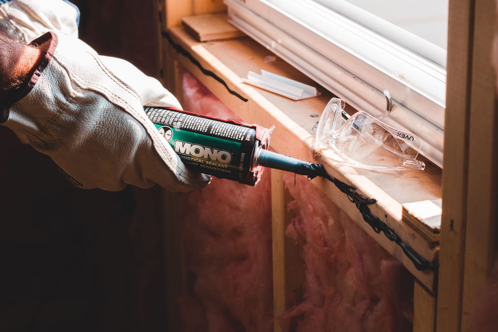 A technician sealing a gap around a window frame — exclusion work that keeps pests out